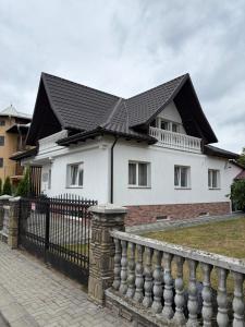 a white house with a black roof and a fence at Vacation with Purpose in Gura Humorului