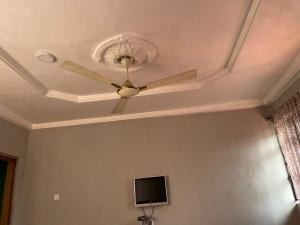 a ceiling fan in a room with a tv at ODeTTe GUEST HOUSE in Kumasi +15 photos