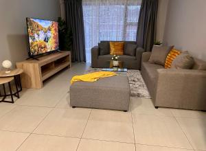 a living room with two couches and a flat screen tv at Nova Apartments- MbabaneCBD in Mbabane