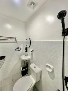 a white bathroom with a toilet and a sink at J&D Fully-Aircon 400mbps Parking WiFi 6pax in Canaman +13 photos
