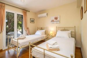 two beds in a room with a window at Villa Emelisse by Villa Plus in Fiskardo