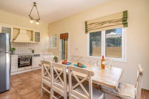 a kitchen with a wooden table and a large window at Villa Emelisse by Villa Plus in Fiskardo
