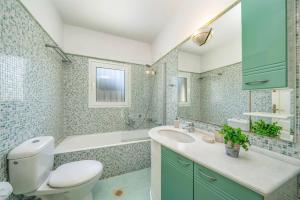 a bathroom with a toilet and a sink and a tub at Villa Emelisse by Villa Plus in Fiskardo +25 photos