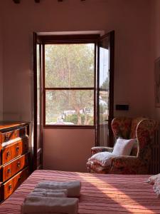 a bedroom with a bed and a window and a chair at Podere Ortacavoli in Terriccio