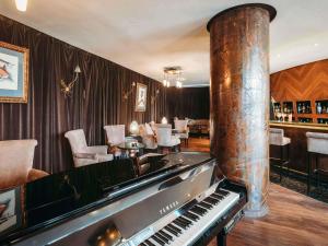 a room with a piano and a bar with chairs at Le Diwan Hotel Rabat - MGallery Collection in Rabat