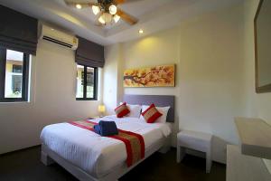 a bedroom with a large white bed with red pillows at Chaba Villa at Had Yao Beach in Had Yao Beach