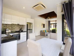a kitchen and dining room with a white table and chairs at Chaba Villa at Had Yao Beach in Had Yao Beach