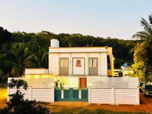 a white house with a fence in front of it at Yelagiris Honey Stay in Yelagiri
