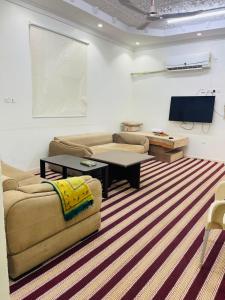 a living room with two couches and a flat screen tv at اجنحة رحال لشقق الفروشة in Medina