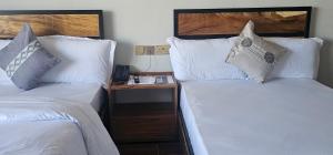 two beds with white pillows and a telephone in a room at Cornerstone Hotel Arusha in Arusha