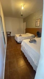 two beds sitting in a room with a tile floor at Quarto com varanda privada a 160 metros da Praia do Farol da barra 3 in Salvador