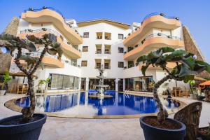 a hotel with a swimming pool in front of a building at Hotel Paradise KMA in Bouznika