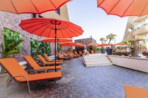 a row of orange chairs and umbrellas on a patio at Hotel Paradise KMA in Bouznika