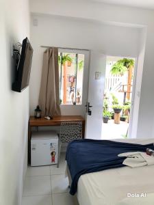 a bedroom with a bed and a desk and a window at Pousada Mel in Praia do Forte