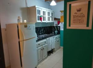 a kitchen with white cabinets and a white refrigerator at casa en toninas in Las Toninas