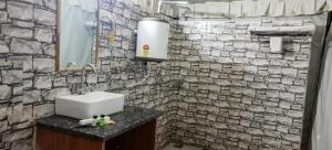 a bathroom with a sink and a stone wall at The Jungle Enclave Boho in Khilchipur +20 photos