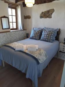 a bedroom with a large bed with blue sheets and pillows at La Petite Grange in Langourla