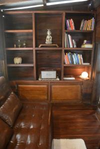 a living room with a leather couch and book shelves at Sunny Mountain in Ban Nong Hoi