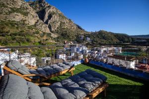 a balcony with blue pillows and a view of a mountain at Alojamientos Chaouni in Chefchaouen