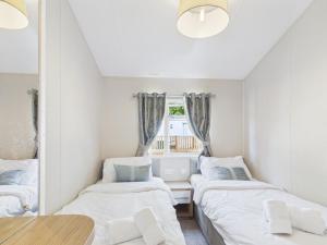 two beds in a small room with a window at Pinehurst, 65 Golf View Lodge in Jedburgh