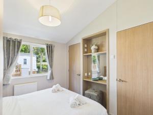 a bedroom with two white beds and a window at Pinehurst, 65 Golf View Lodge in Jedburgh
