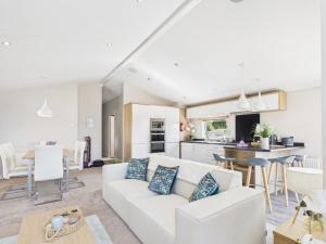 a living room with a white couch and a kitchen at Pinehurst, 65 Golf View Lodge in Jedburgh +22 photos