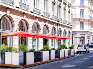a building with red umbrellas on a city street at Mercure Lyon Centre Plaza République in Lyon