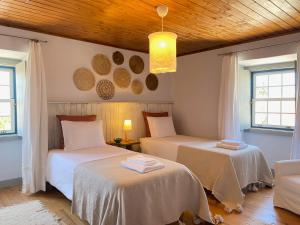 a bedroom with two beds and a wooden ceiling at Casa do Chafariz in Torres Vedras