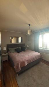 a bedroom with a large bed with a pink blanket at Akranes Sunset Apartment in Akranes