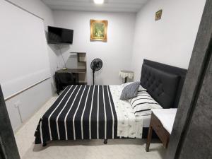 a bedroom with a black and white bed and a desk at Casa hotel la 33 in Medellín