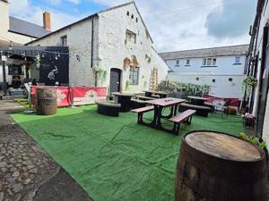 a patio with a table and benches on a green lawn at Graham Arms Inn in Longtown