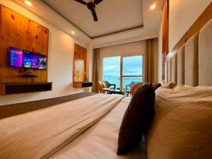 a bedroom with a large bed with a tv on the wall at Pine View Luxury Resort With Mountain View & Premium Rooms Mussoorie in Mussoorie
