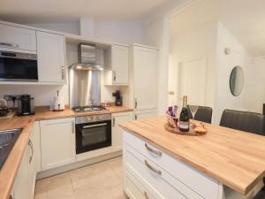 a kitchen with white cabinets and a wooden counter top at Luxury 2 Bedroom Lodge at White Cross Bay, Windermere in Windermere +45 photos