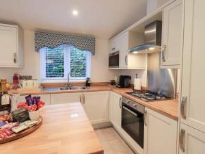 a kitchen with white cabinets and a wooden table at Luxury 2 Bedroom Lodge at White Cross Bay, Windermere in Windermere