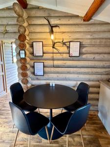a table and chairs in a room with wooden walls at Grasbakken hytteutleie in Nesseby