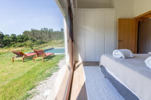 a bedroom with a bed and two chairs and a window at A casa das Ías in Tourón