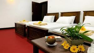 a bedroom with two beds and a table with flowers at Mist Mountain Hiking Base in Pimbura