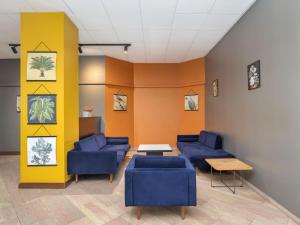 a waiting room with blue couches and a yellow wall at B&B Hotel Como City Center in Como