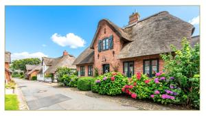an old brick house with flowers in front of it at Lavendelhaus in Oevenum