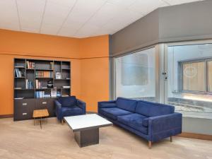 a living room with two blue couches and a book shelf at B&B Hotel Como City Center in Como