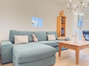 a living room with a blue couch and a coffee table at Reetdachhaus Sünsbarg in Simonsberg