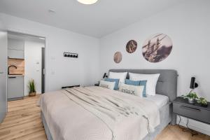 a white bedroom with a large bed with blue pillows at Ferienwohnung TheViewC08 Hygge am Deich Dagebüll in Dagebüll +21 photos