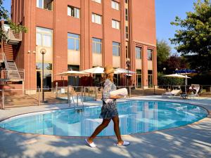 a woman walking by a pool in front of a building at Novotel Torino Corso Giulio Cesare in Turin