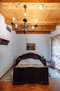 a bedroom with a bed and a ceiling with a chandelier at Hanul Moara cu Noroc in Ineu