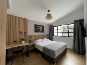 a bedroom with a bed and a desk and a window at Vita Hotel Boutique - Aire Acondicionado & Desayuno in Medellín