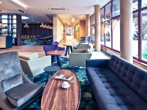 a lobby with a couch and tables and chairs at Mercure Jelenia Góra in Jelenia Góra