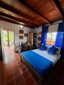a bedroom with a bed with blue curtains and a desk at Hotel Cristo Rey Campestre in Los Santos