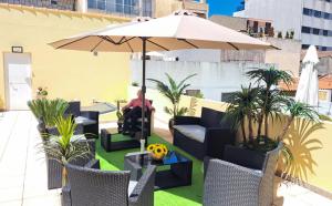 a man sitting in a chair under an umbrella on a patio at Casa Dourado Ramos in Vila do Conde