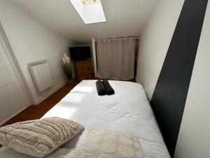 a bedroom with a white bed with a black pillow at Studio Cosy & Chic in Angoulême