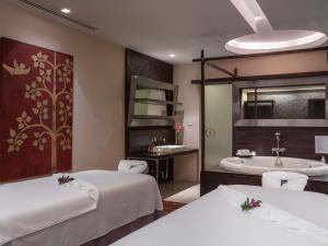 a hotel room with two beds and a bath tub at Pullman Bangkok Hotel G in Bangkok